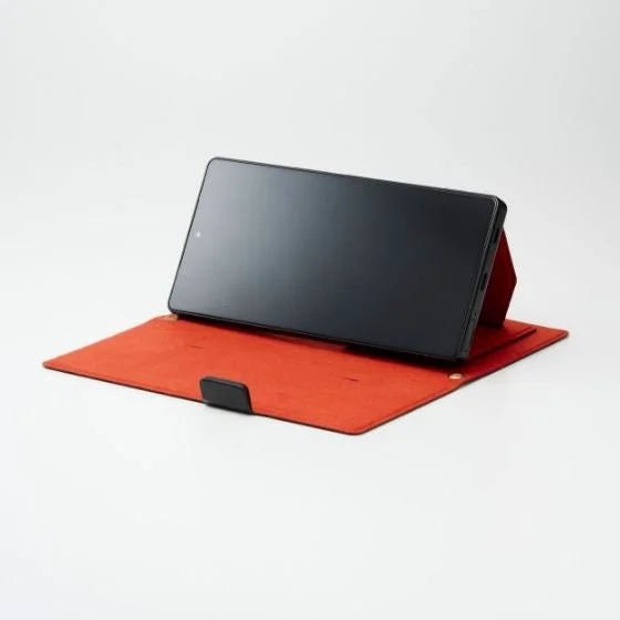 赤い折りたたみ式ケースをスタンドとして使い、横向きに立てられた黒いタブレットまたはスマートフォン