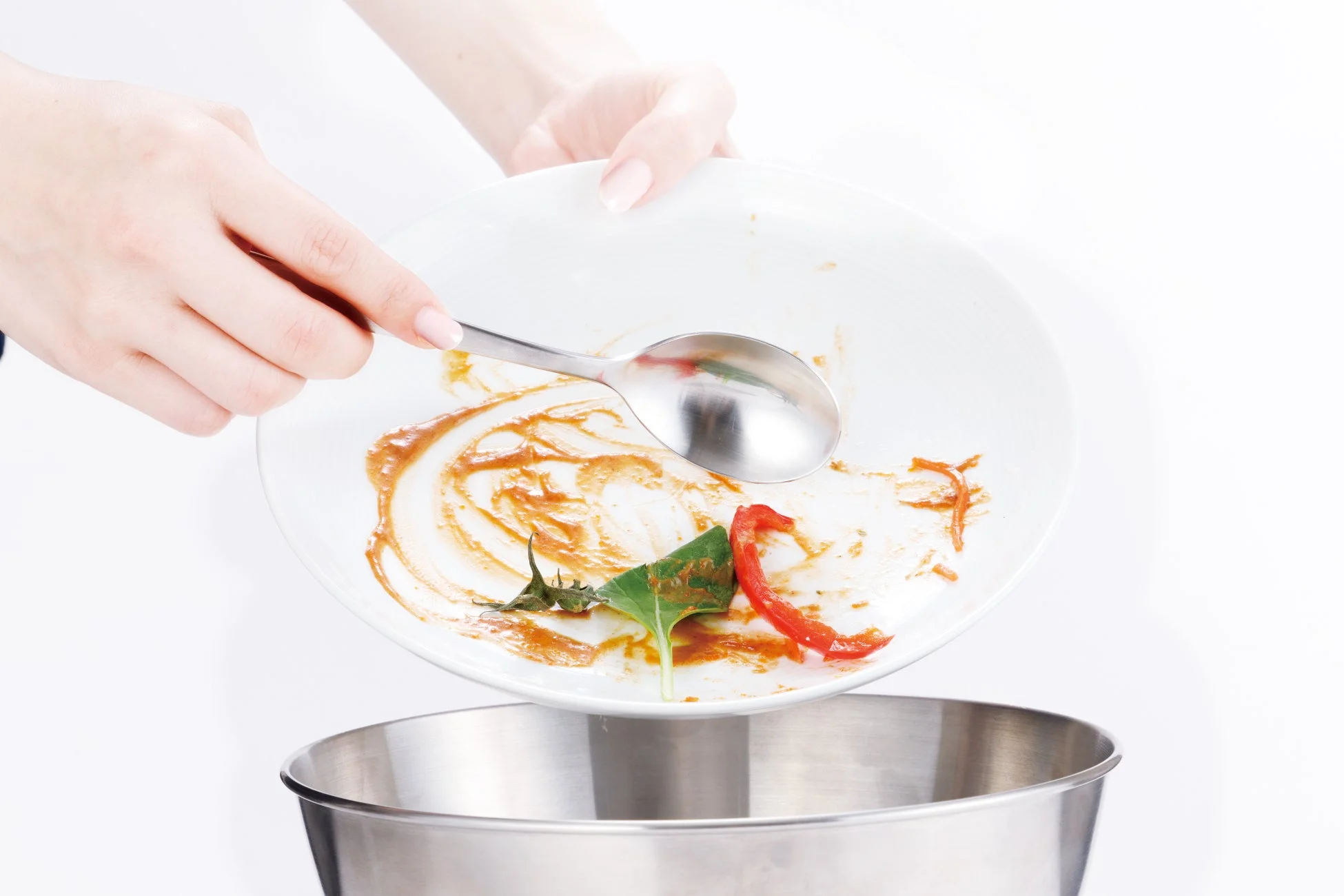 食べ残しの料理が残った皿とスプーンをゴミ箱に捨てている様子