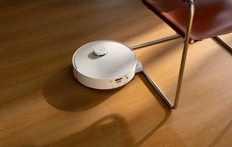 白いロボット掃除機が椅子の近くを掃除している様子
