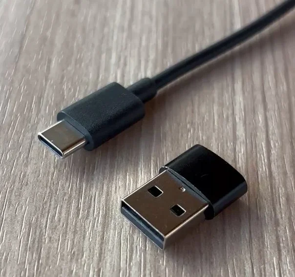 USB Type-CケーブルとUSB-A変換アダプタが木目調のテーブルに置かれた写真