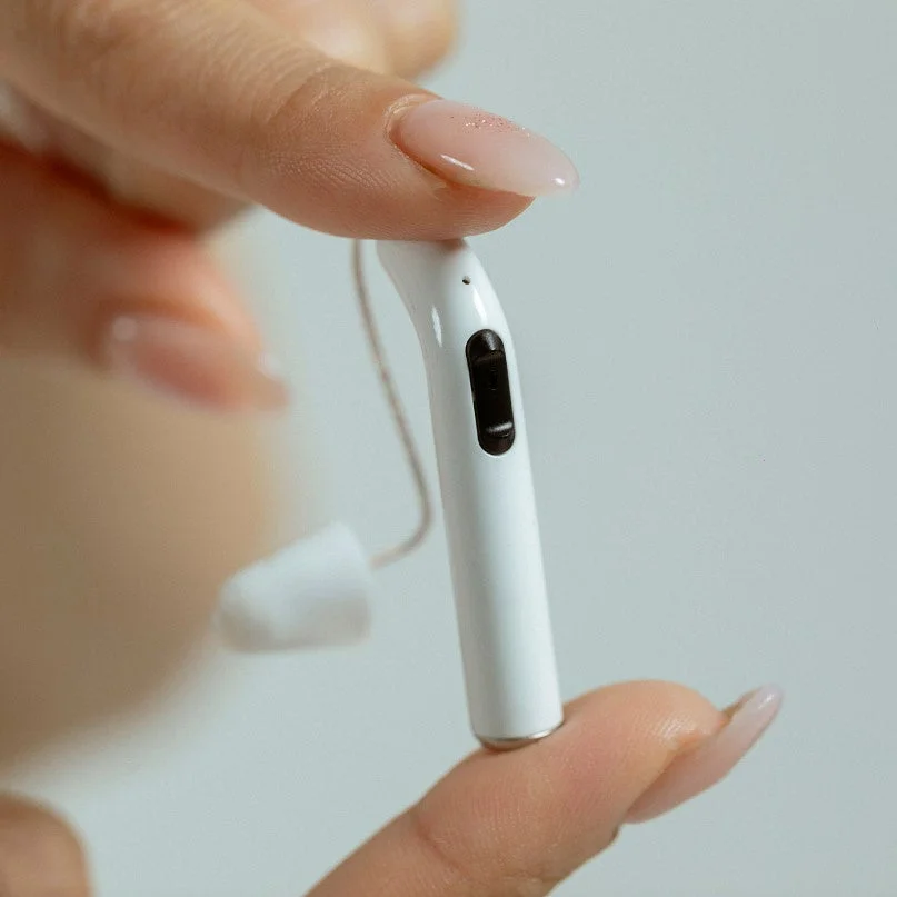 指で挟まれた小型の補聴器