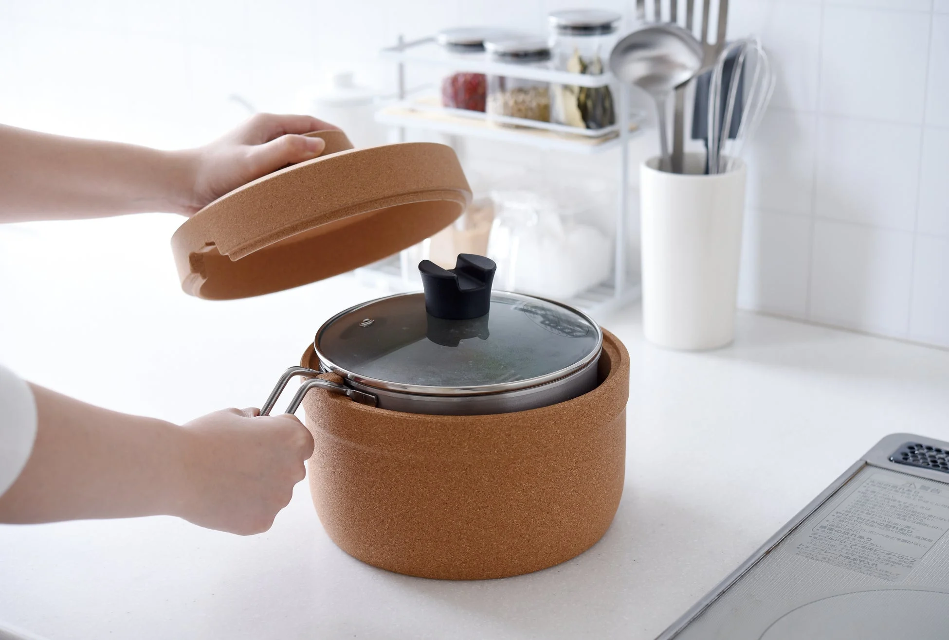 清潔なキッチンで、コルク製の保温容器に入った鍋の蓋を開け閉めしている場面
