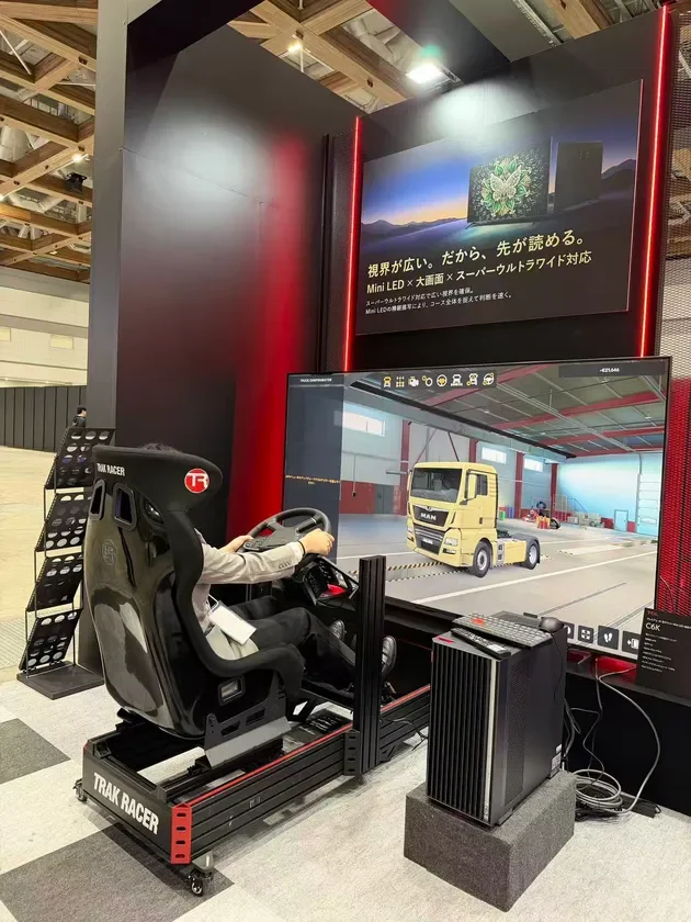 展示会ブースで、Mini LED大画面ディスプレイとTrak Racerのコックピットを使ったトラック運転シミュレーターを体験する男性