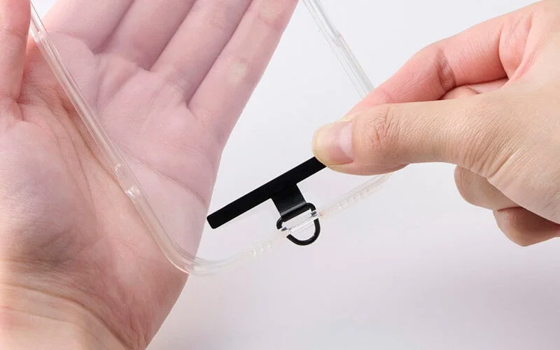 透明なスマートフォンケースの充電ポート部分にDリング付きホルダーを装着している様子