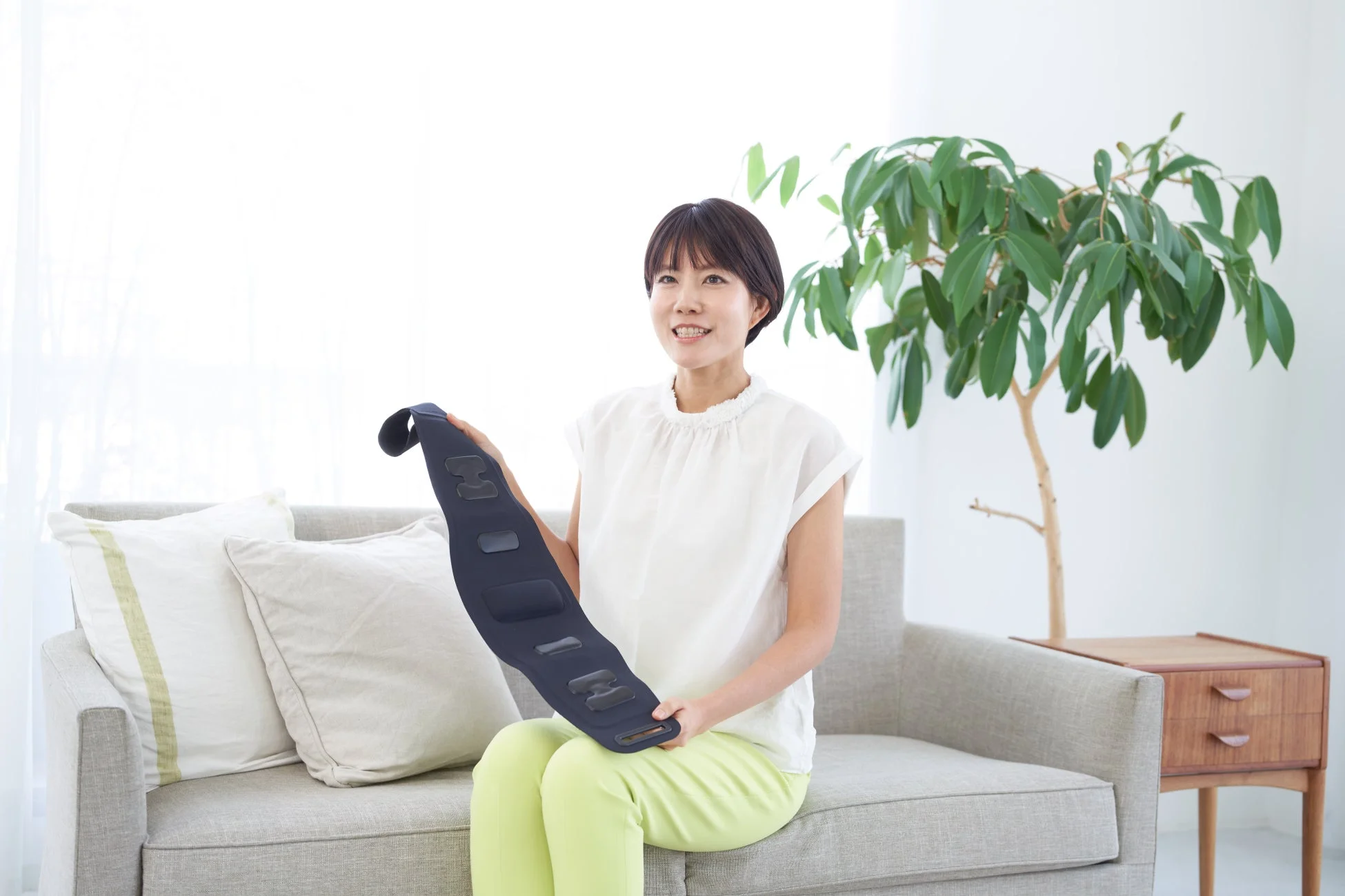 リビングでブーストブレスベルトを手に笑顔を見せる女性