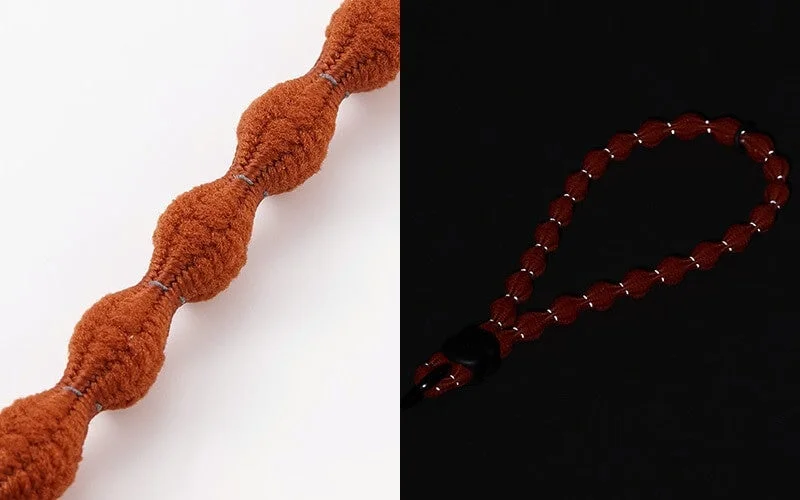 白と黒の背景にオレンジ色の波状の紐と反射材の白い点が見える赤茶色の紐