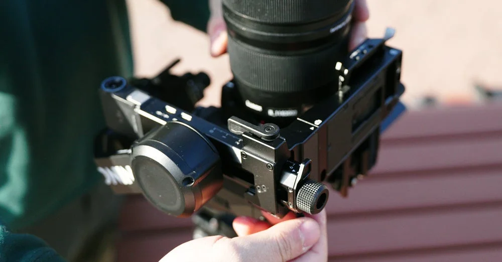 カメラとレンズがジンバルに取り付けられ、手によって調整されている様子