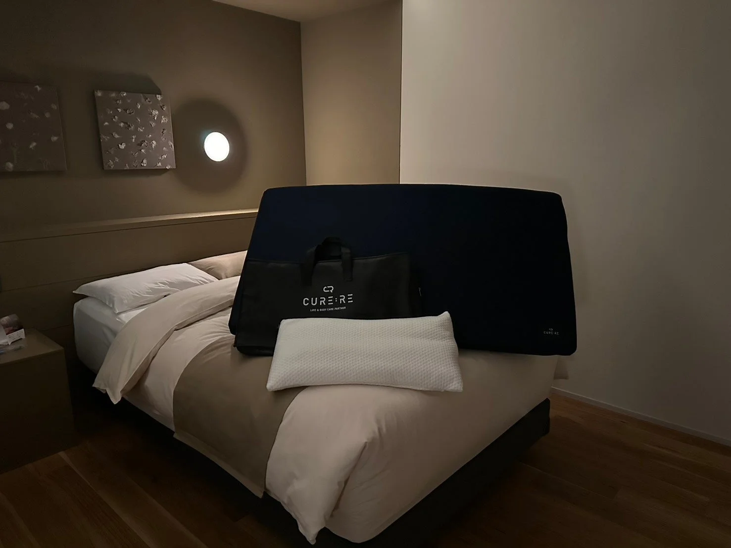 落ち着いた雰囲気の寝室に置かれたベッドとCURE:REロゴのバッグ