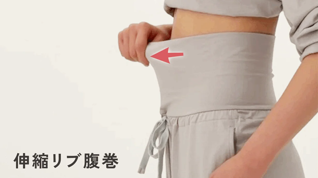 ライトグレーのリブ腹巻を着用した人物が、その伸縮性を手で引っ張って示している画像です。