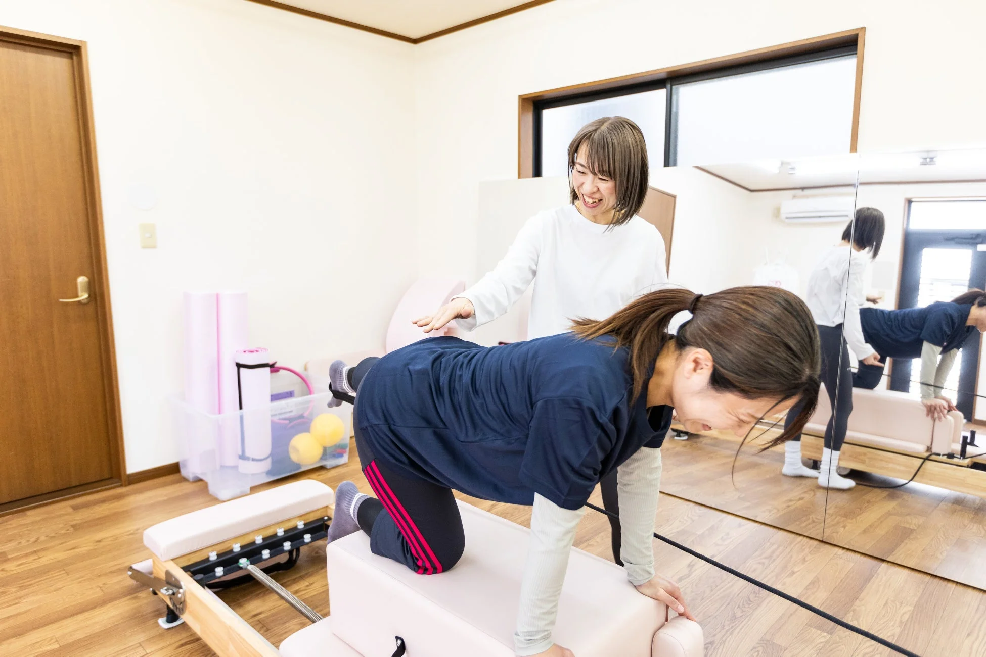 明るいスタジオでピラティスリフォーマーを使ってトレーニングを受ける女性