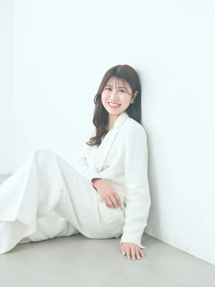 白いスーツを着て座っている女性