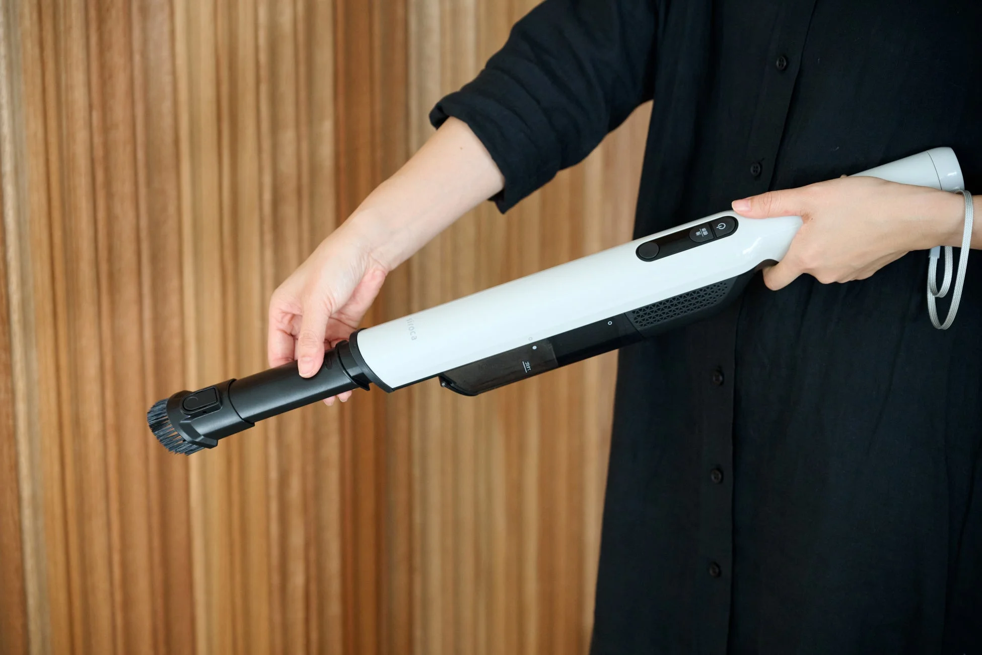 白いハンディクリーナーを手に持ち、ブラシ部分を調整している人物