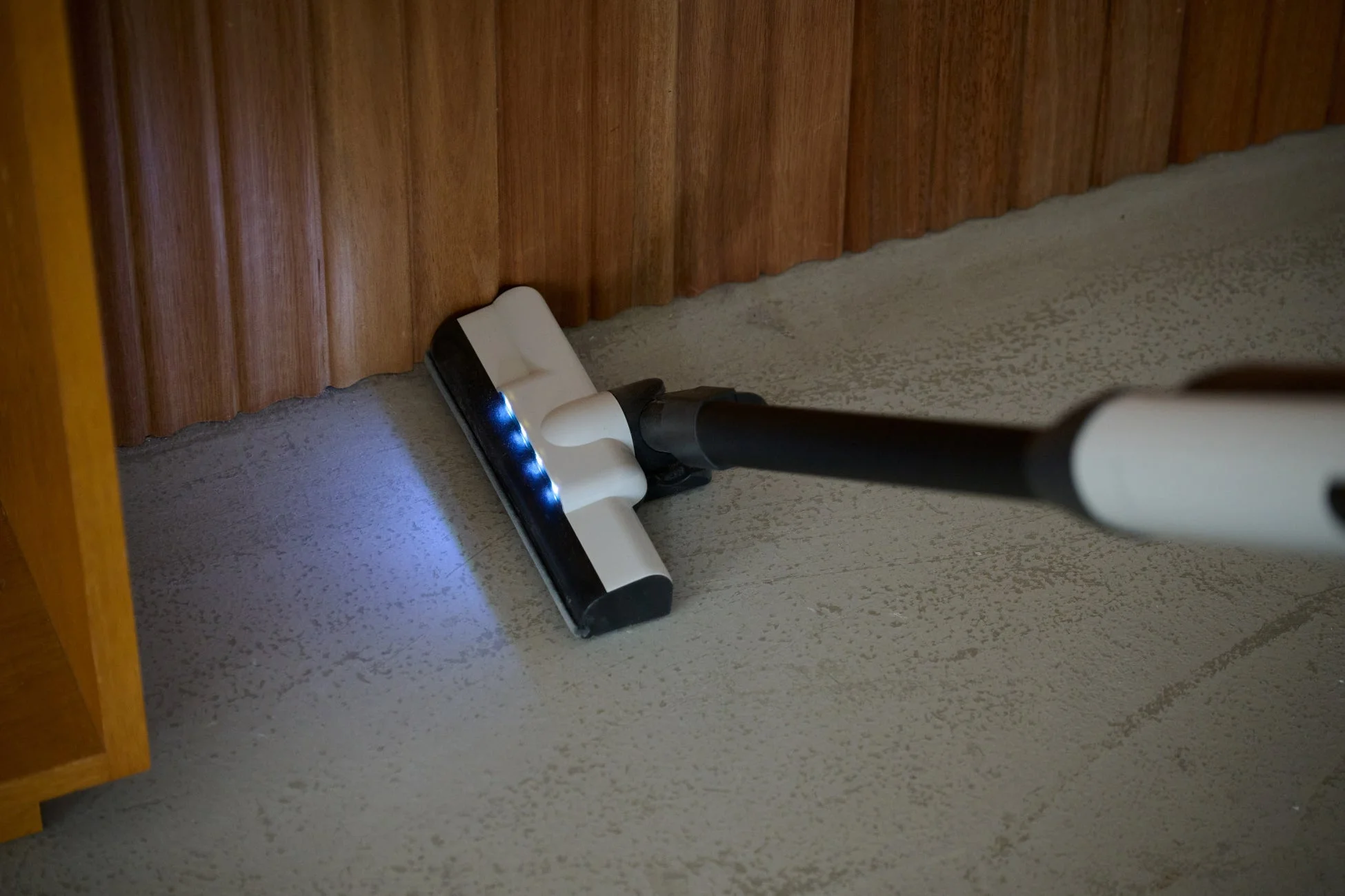 LEDライトが点灯している掃除機のヘッドが壁際を清掃している様子