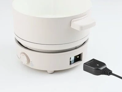 白い電気鍋が白い背景に置かれており、電源コードが本体から外れた状態が写っています。