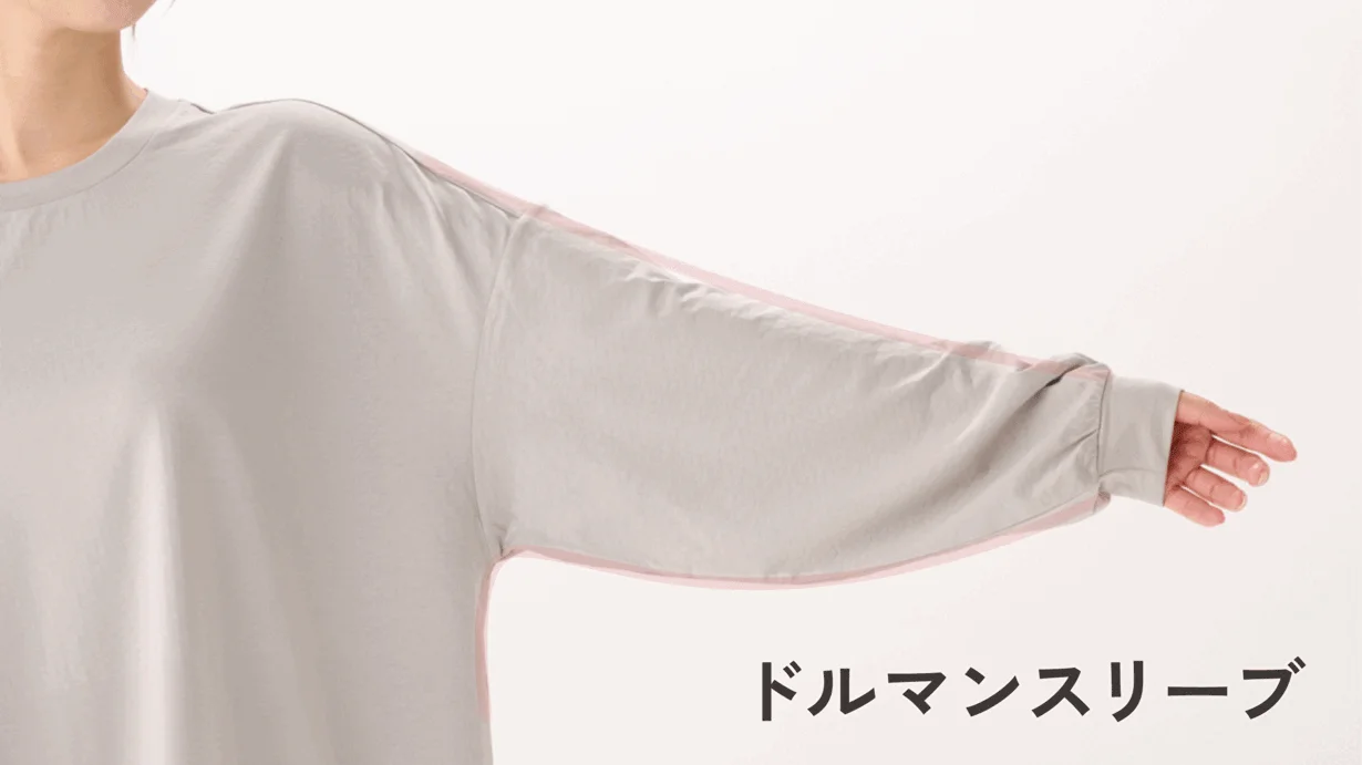 グレーのドルマンスリーブのトップスを着た人物の腕元を写した画像です。