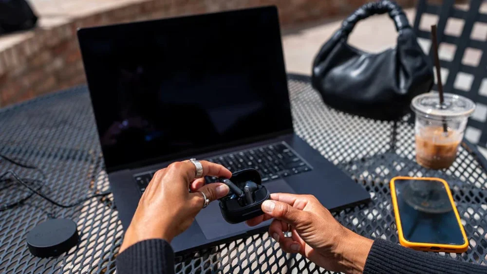 イヤホンを装着しノートパソコンとスマートフォンを使用する人