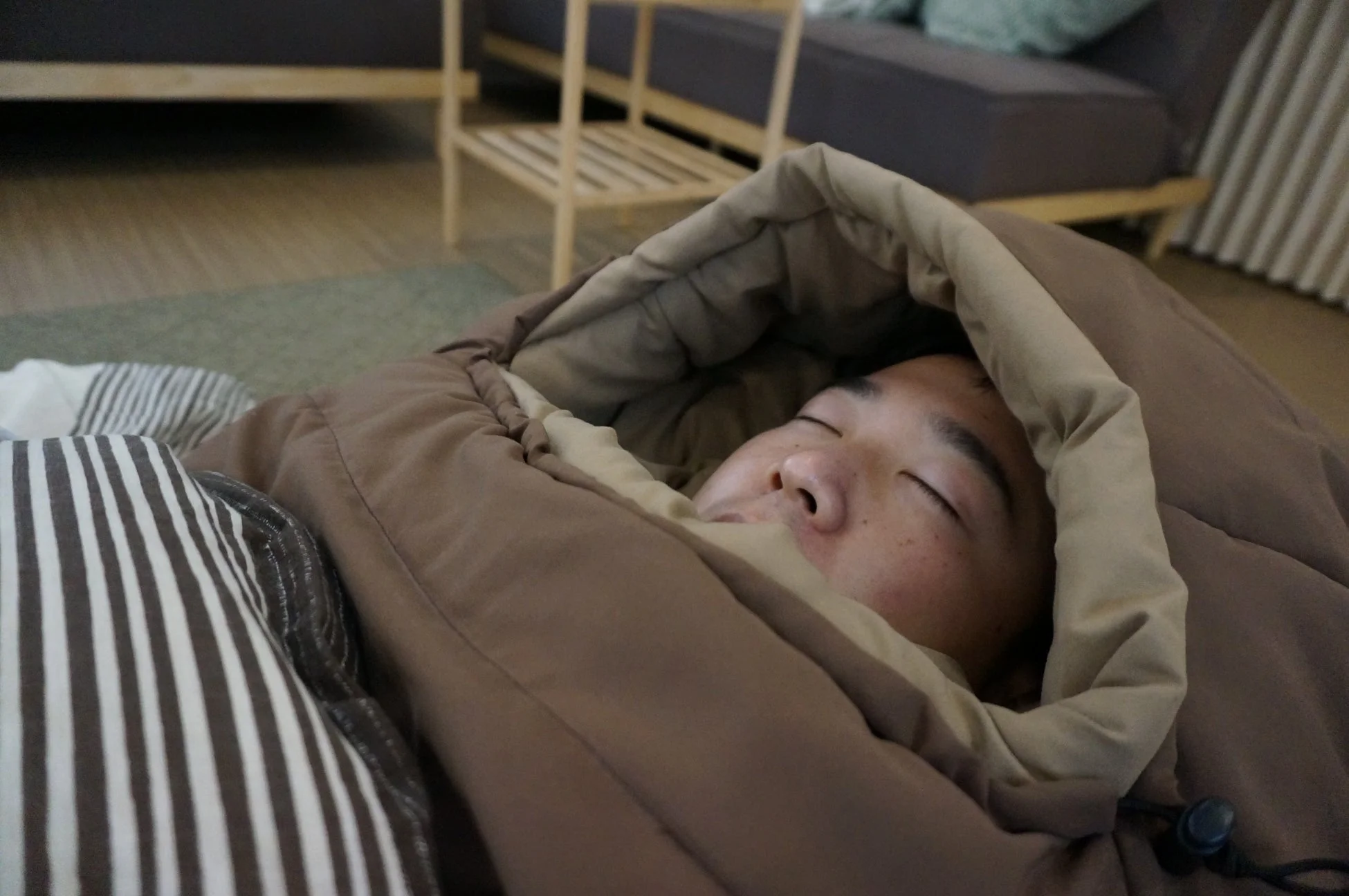 寝袋にくるまって眠る人物