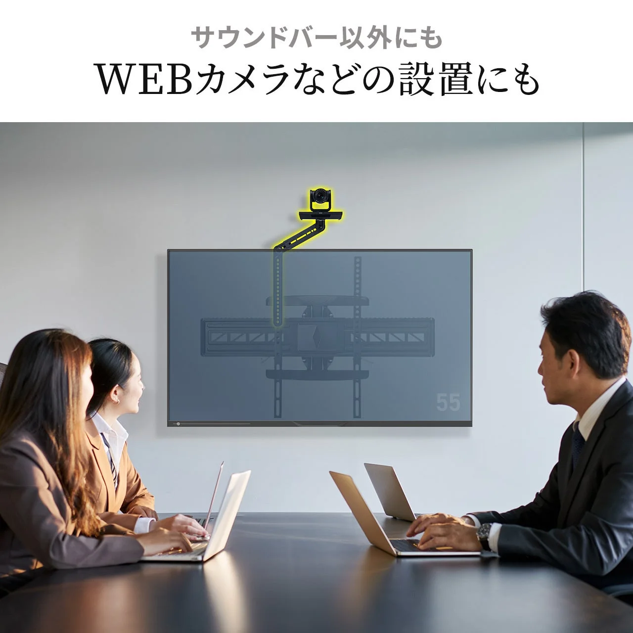 会議室でビジネスパーソン3人がディスプレイを見ている様子。ディスプレイ上部にはウェブカメラが設置されており、サウンドバーだけでなくウェブカメラの設置にも対応していることを示すテキストが表示されています。