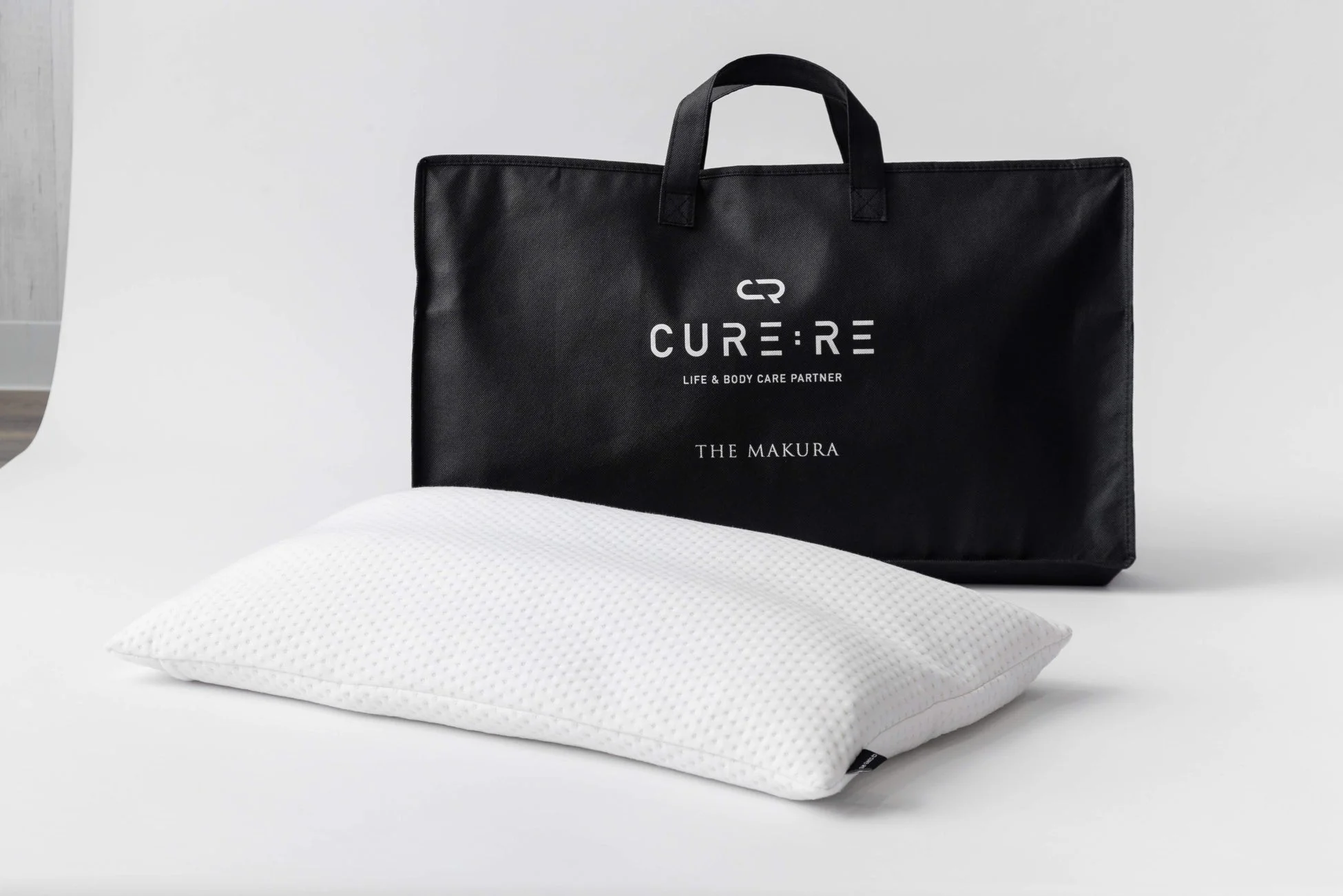 白い枕とCURE:RE、THE MAKURAのロゴが入った黒いバッグ