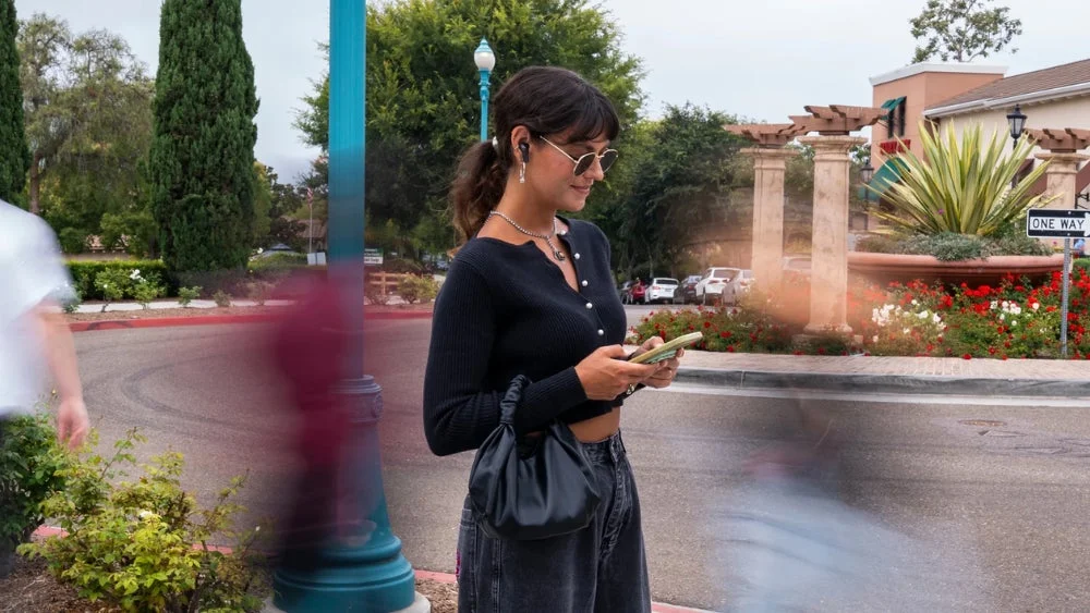 イヤホンを装着して街を歩く女性