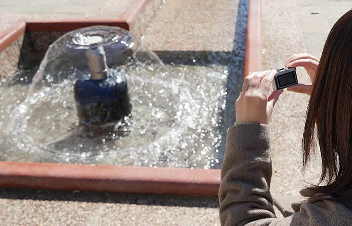 カメラで噴水を撮影する女性