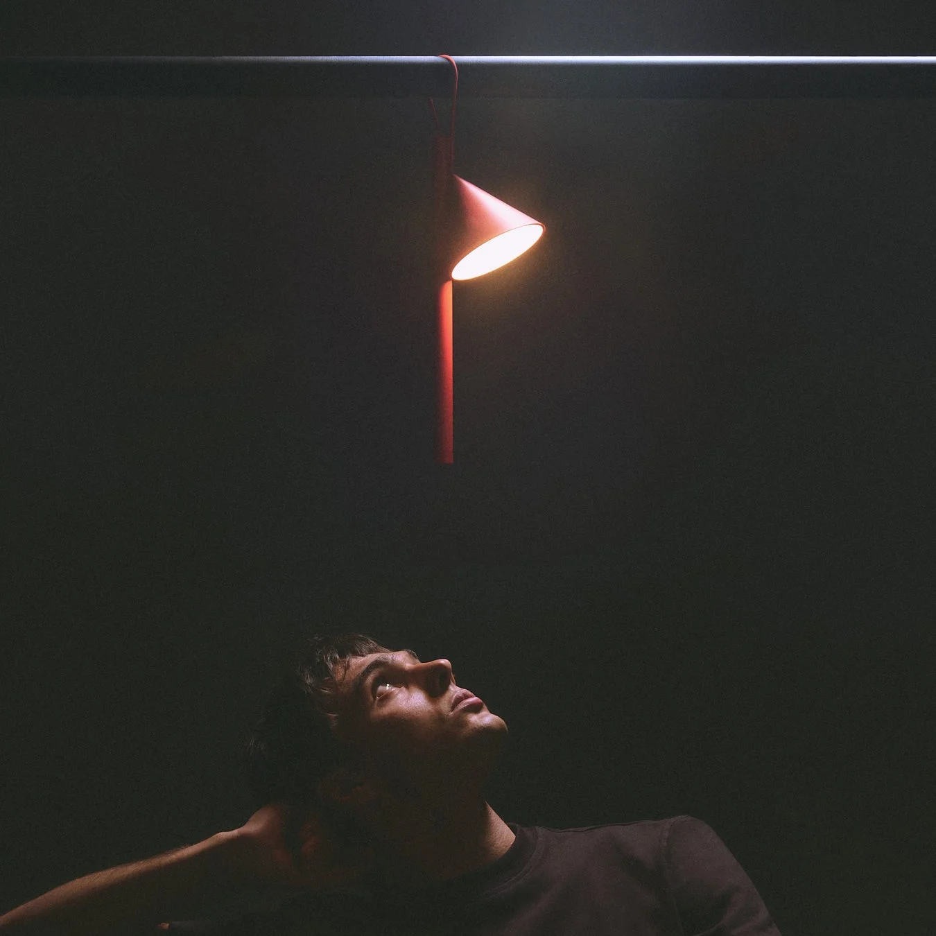 暗い空間で赤いランプを見上げる男性
