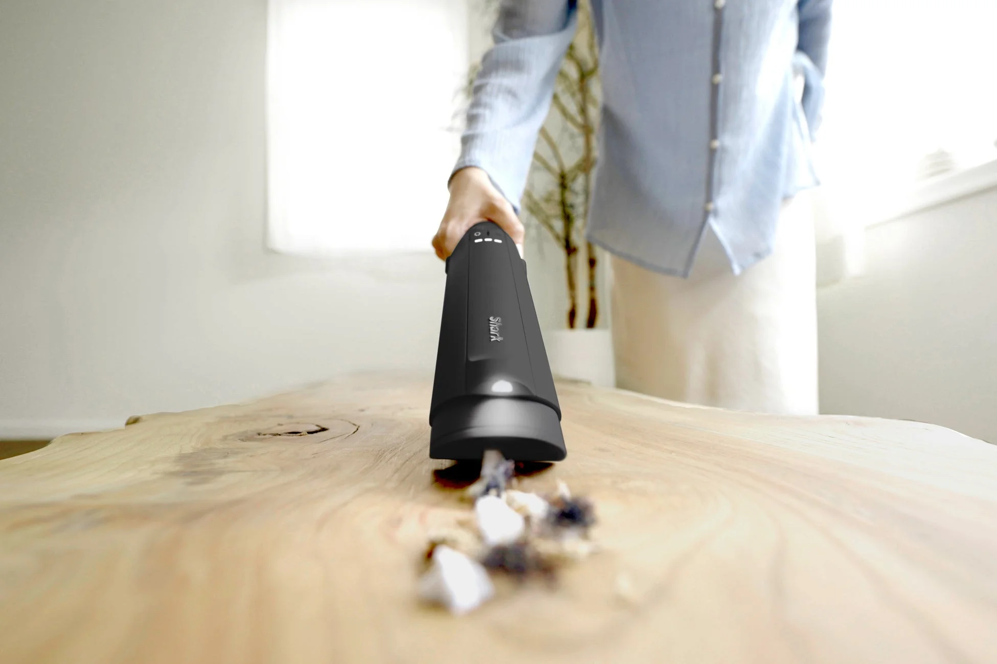 ハンディクリーナーでテーブルのゴミを吸い取る様子