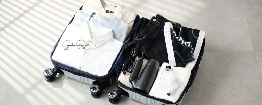 開いたスーツケースの中に衣類や小物とドライヤーが収納されている