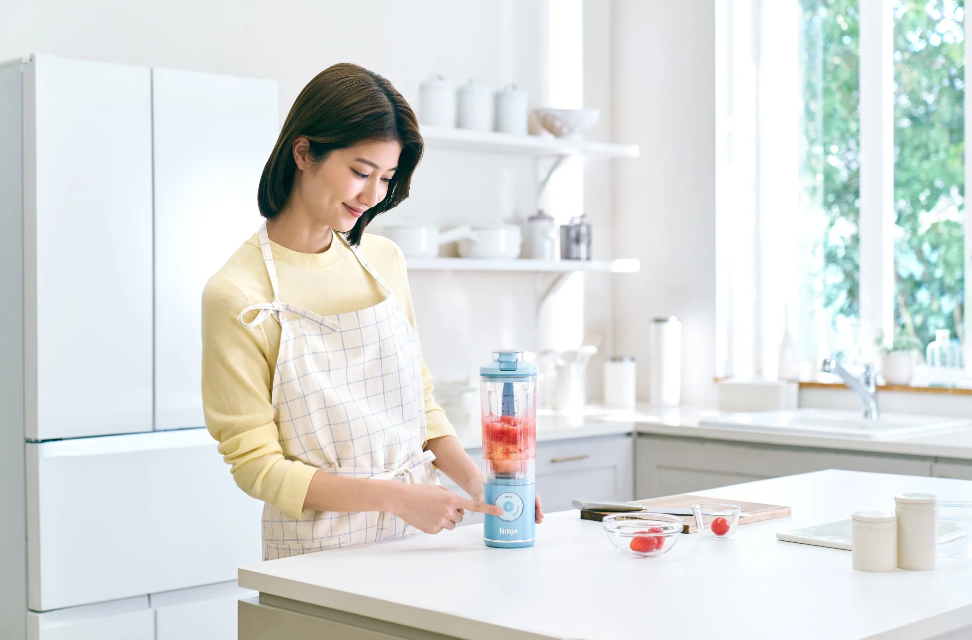 キッチンでブレンダーを使う女性