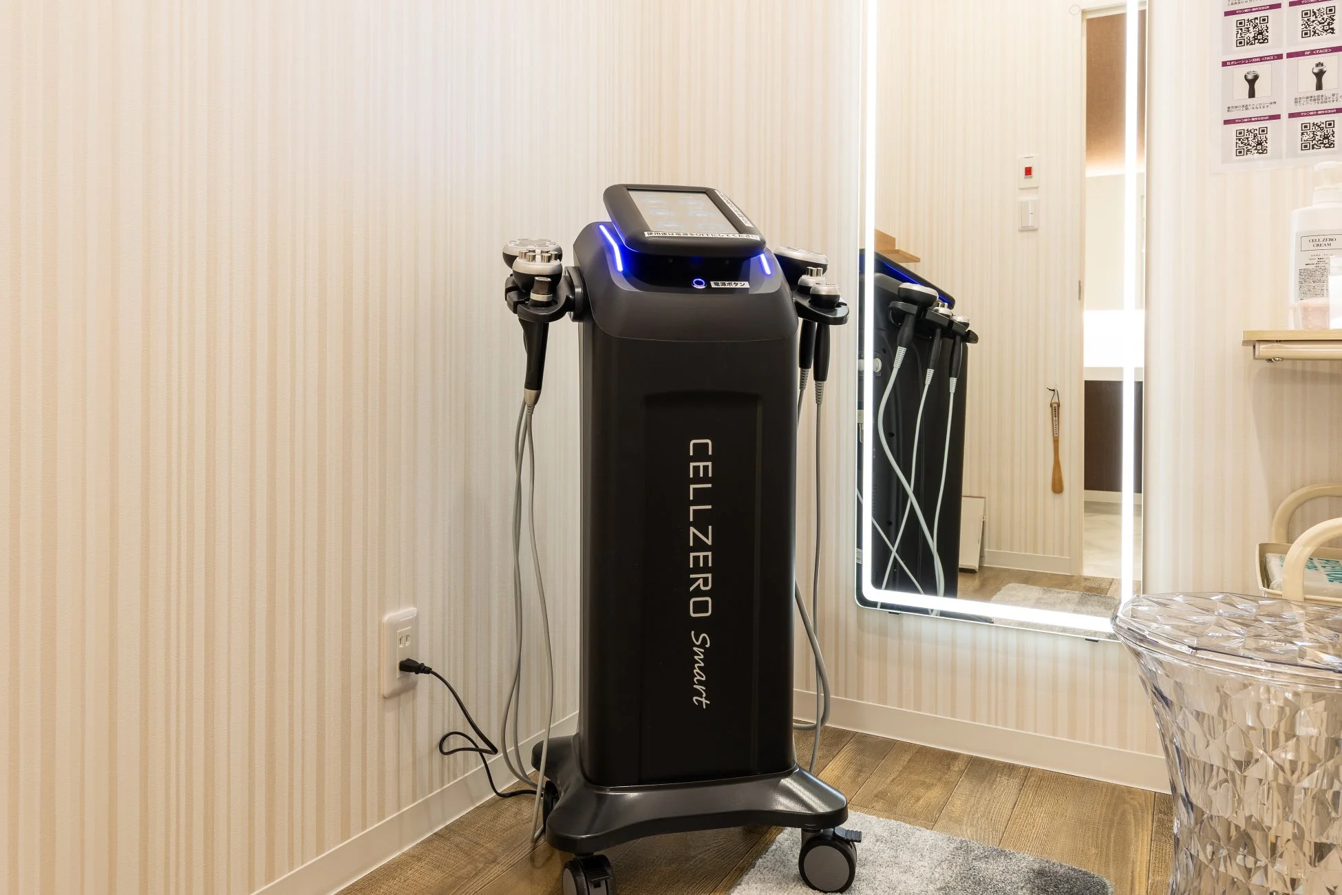 エステサロンのような個室に設置された黒い多機能美容機器「CELLZERO Smart」。鏡や美容クリームが置かれた清潔感のある空間です。