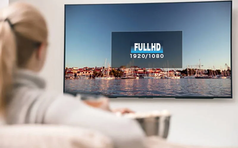 ソファでリラックスする女性がポップコーンを食べながらテレビを視聴している