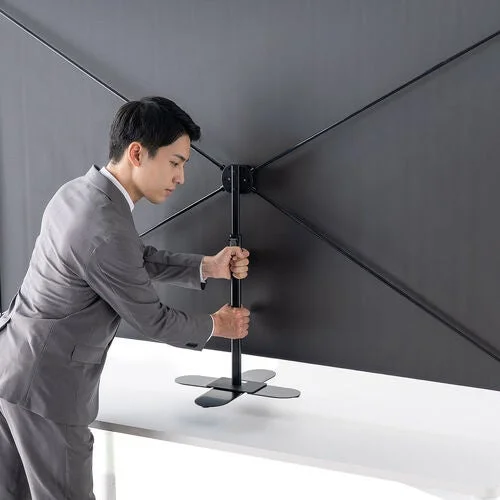 スーツの男性が黒い背景スタンドを組み立てている様子