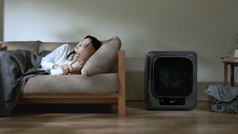 ソファで眠る女性と乾燥機