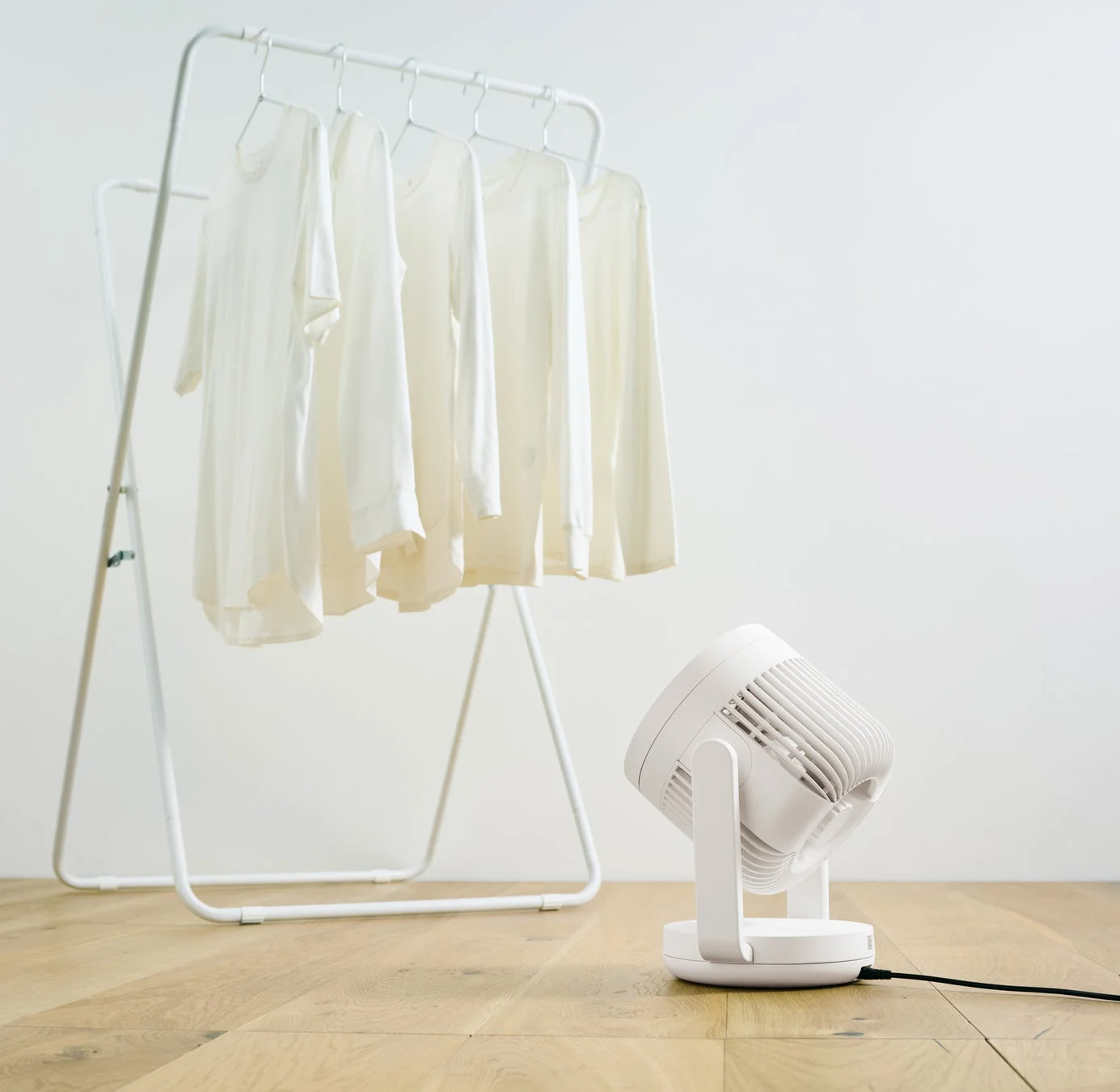 部屋干しされた洗濯物に風を送るサーキュレーター