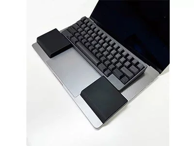 ノートパソコンの上に外付けキーボードとリストレストが配置された作業環境
