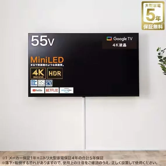 白い壁に設置された55V型MiniLED 4K HDR Google TVの壁掛けテレビ。YouTubeやNetflixに対応し、5年保証無料の案内も含まれている。