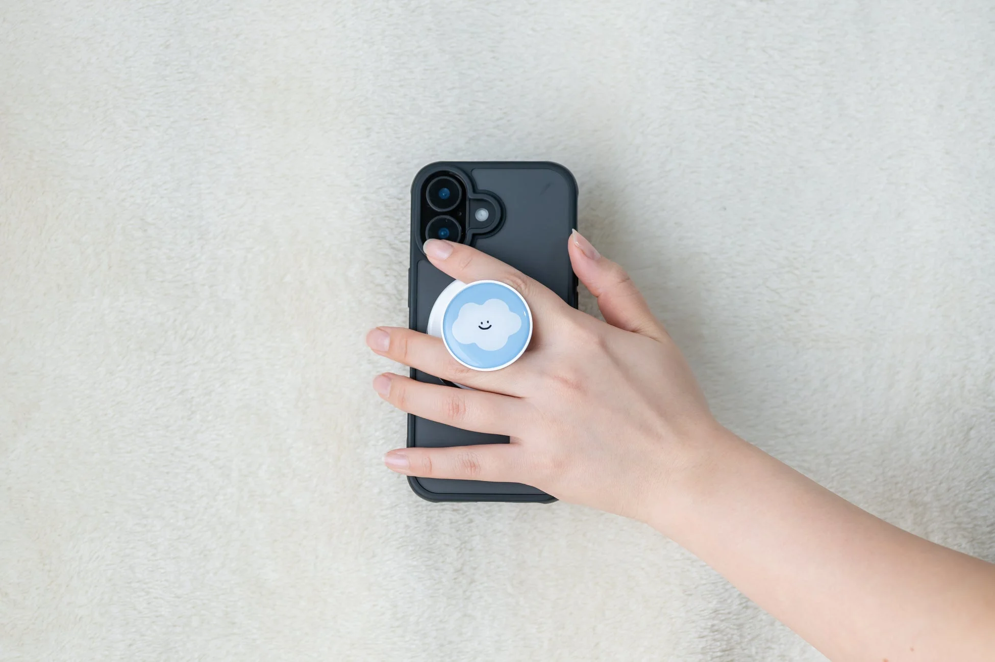 雲のイラストのスマホグリップを持つ手