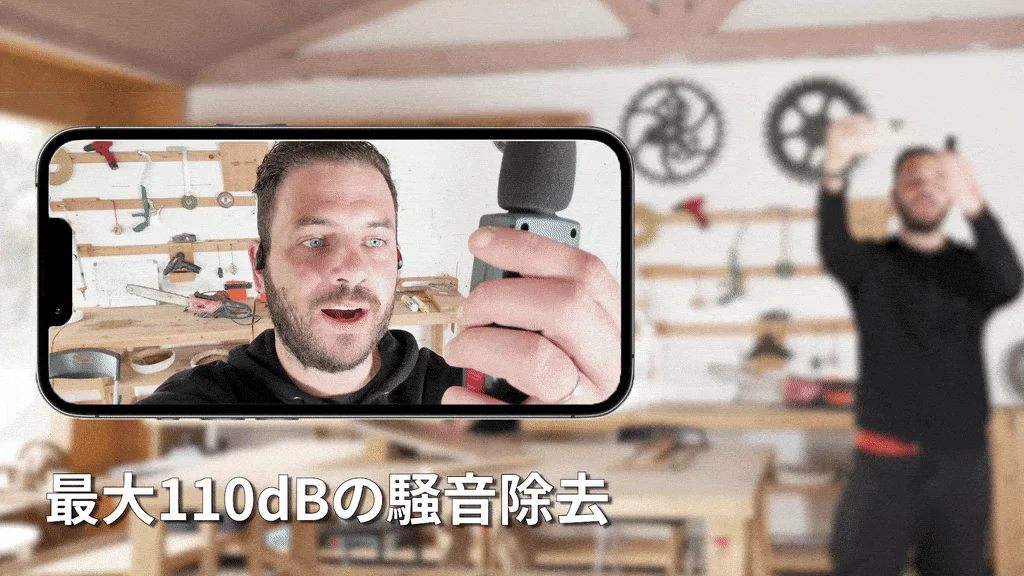 スマートフォン画面にワークショップで作業する男性が映し出され、手にはマイクのようなデバイスを持っている