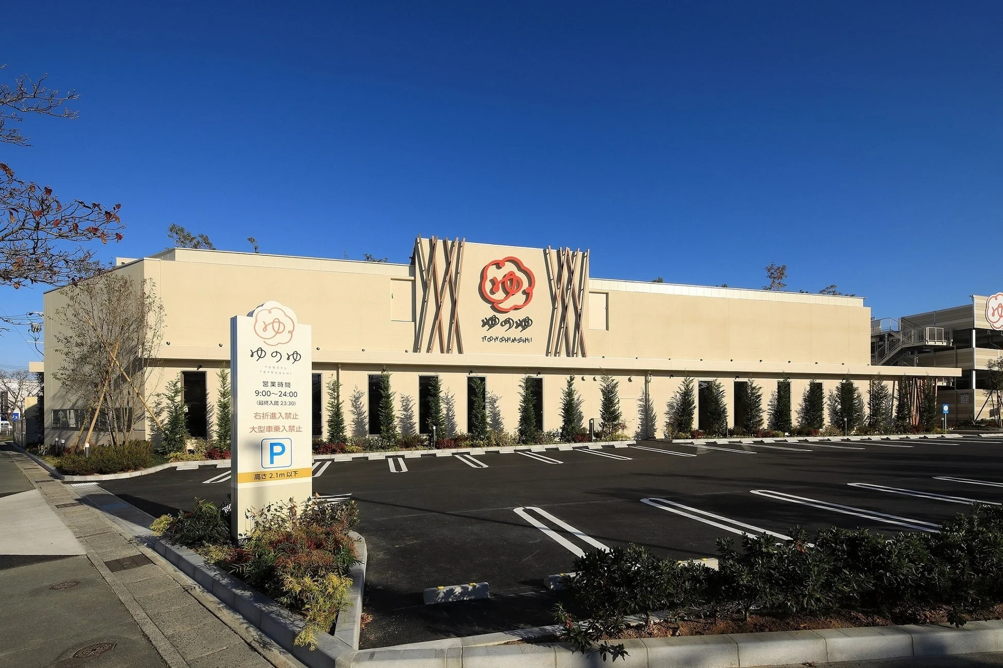 「ゆのゆ TOYOHASHI」という温浴施設らしき建物の外観と、広々とした駐車場