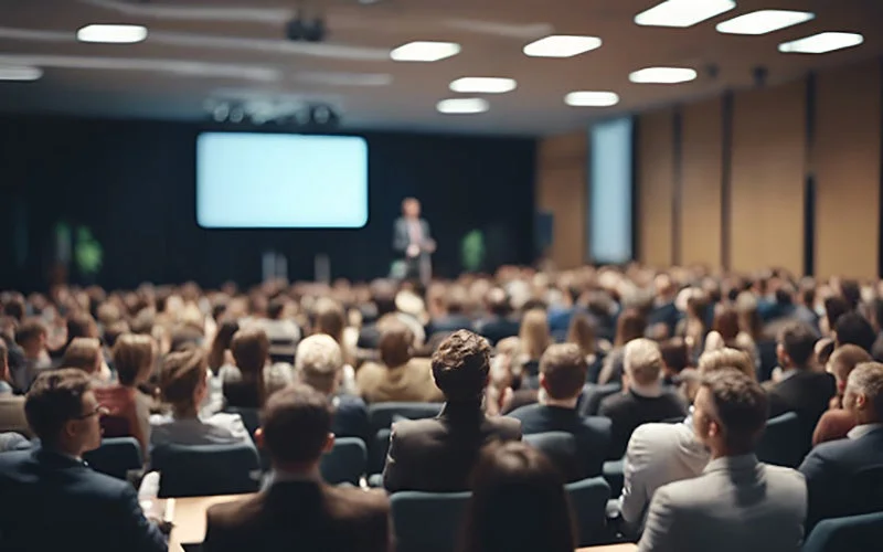 広い会場で大勢の聴衆がプレゼンテーションを聴いている様子