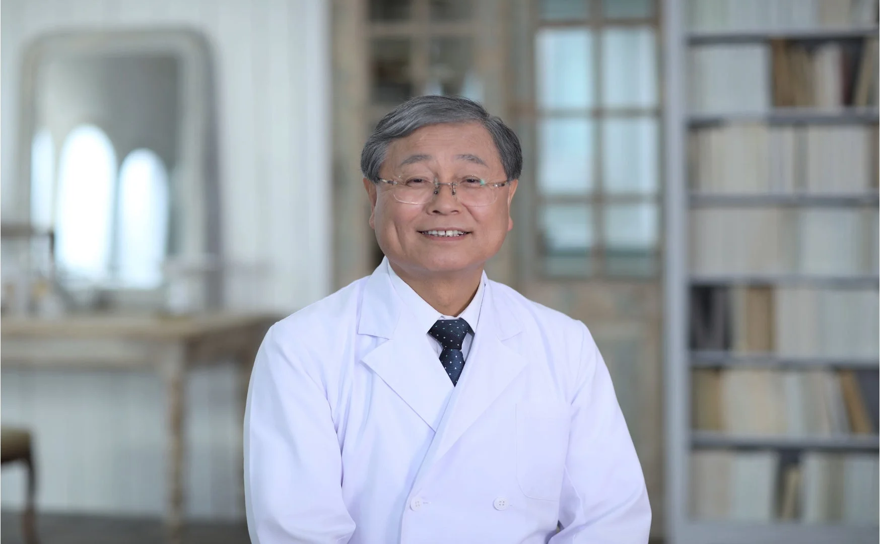白衣を着て眼鏡をかけた笑顔の中高年男性