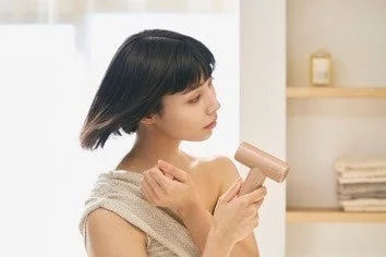 バスルームでドライヤーを使う女性