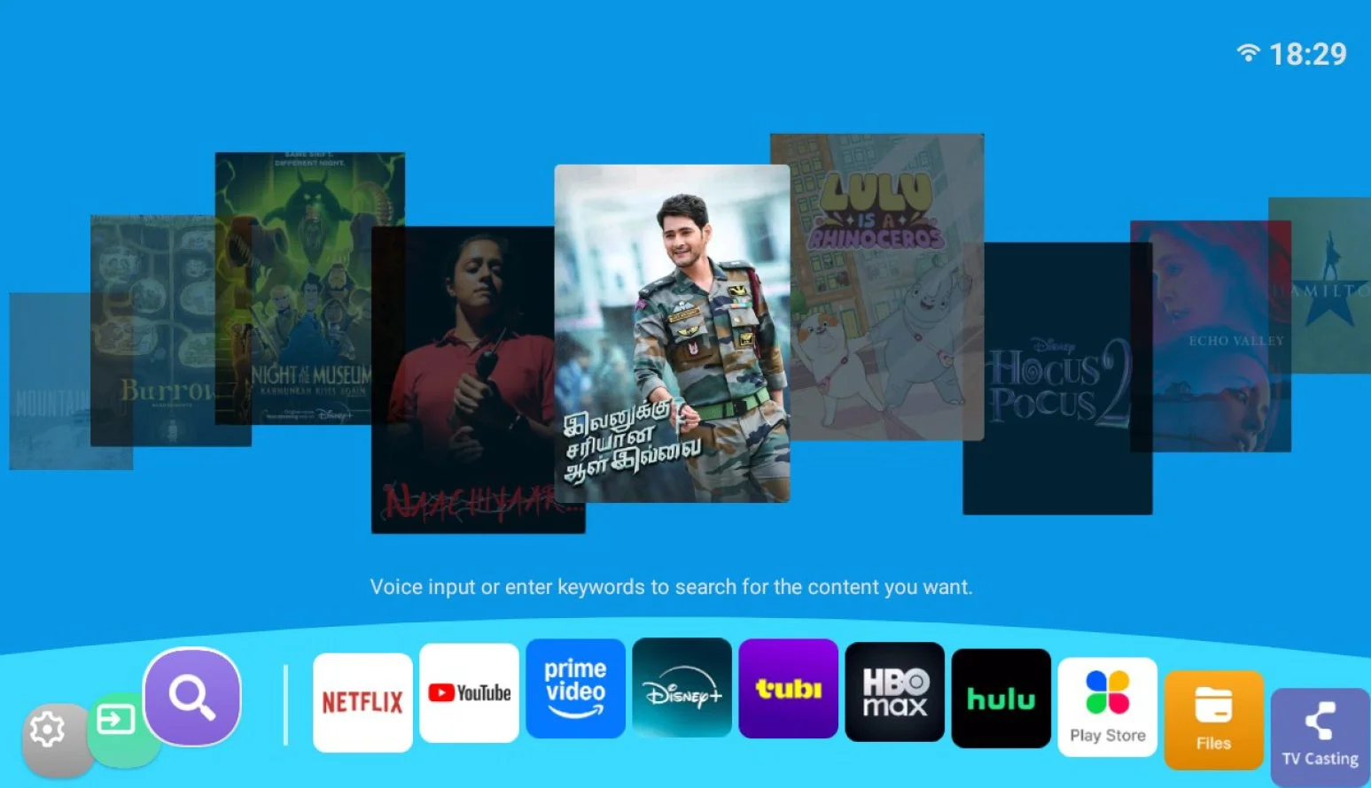 スマートテレビのホーム画面で、映画やドラマのポスターがカルーセル表示され、Netflix、YouTube、Disney+など主要なストリーミングアプリが並んでいます。コンテンツ検索機能も備えたユーザーインターフェースです。