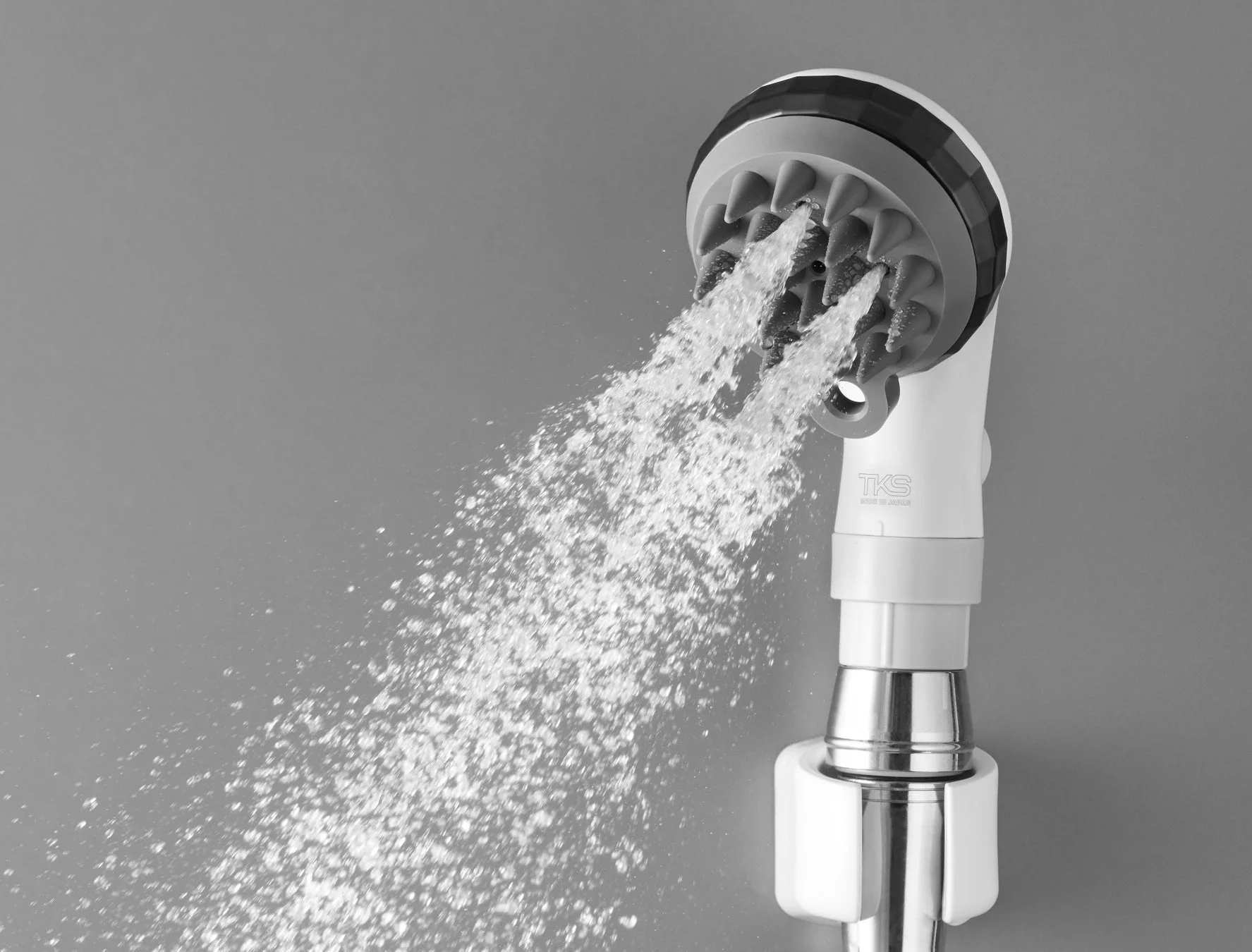 モノクロで撮影されたシャワーヘッドが勢いよく水を噴射している様子。