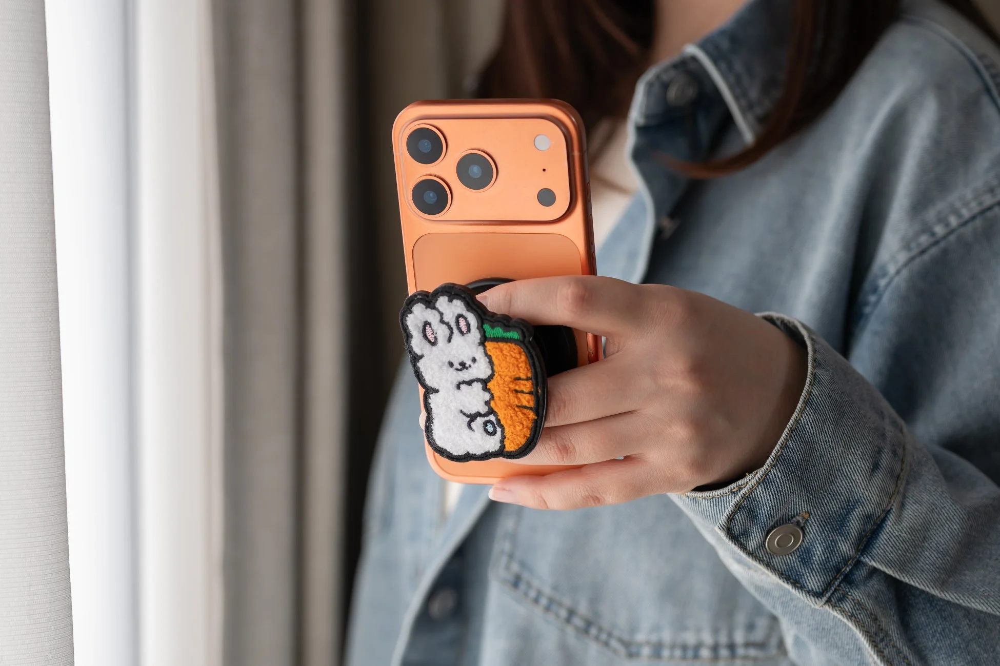 ウサギとニンジンのスマホグリップを持つ手