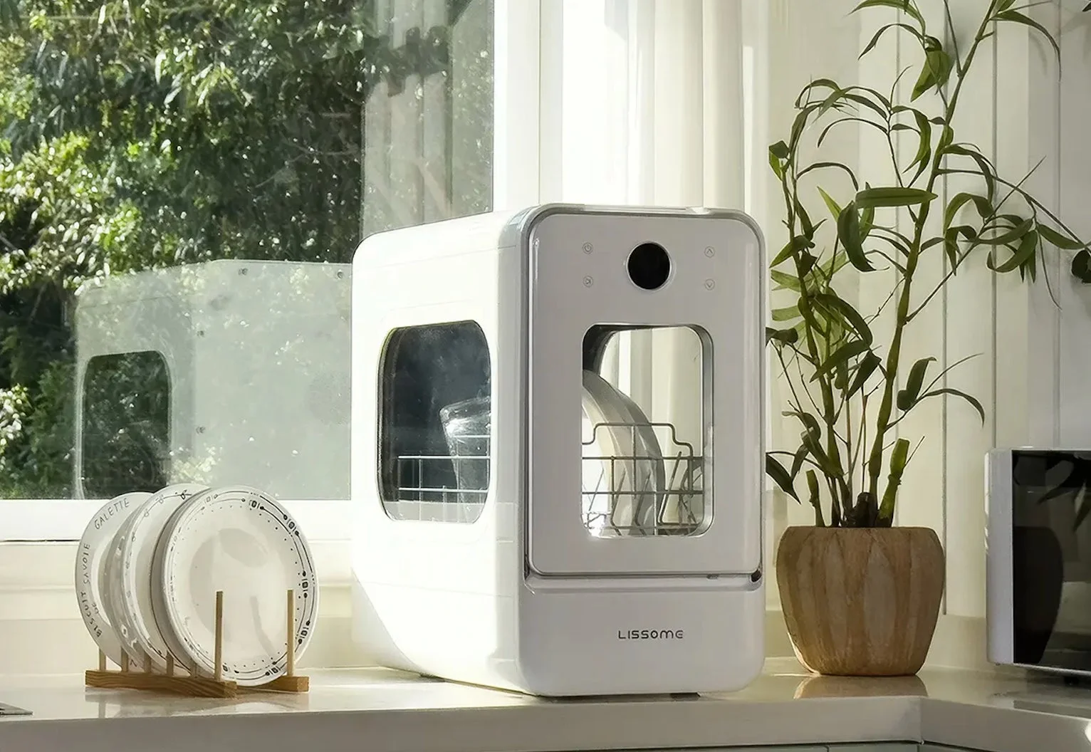 明るいキッチンカウンターに置かれた白いコンパクトな食洗機