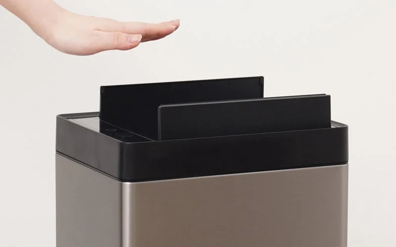 非接触型の自動開閉式ゴミ箱または同様のデバイスの上で、手がセンサーに反応している様子