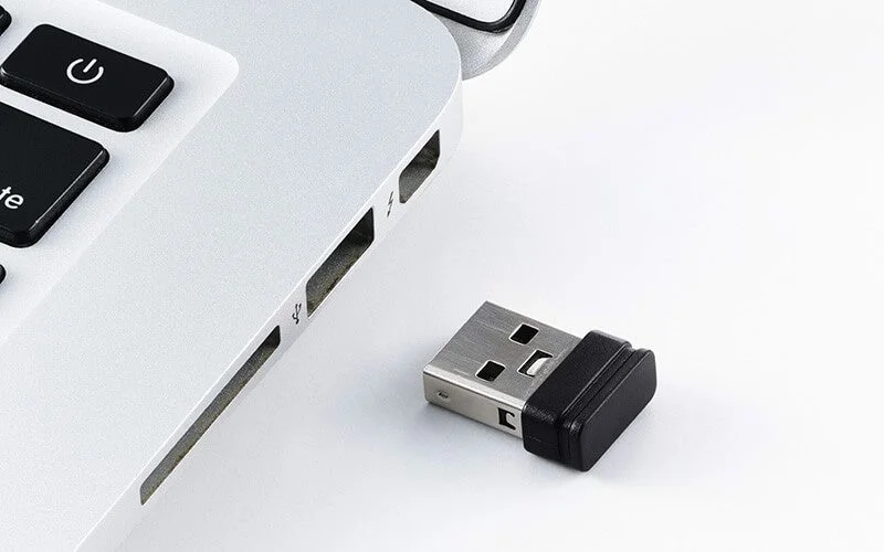ノートパソコンの側面と、その隣に置かれた小型のUSBドングル