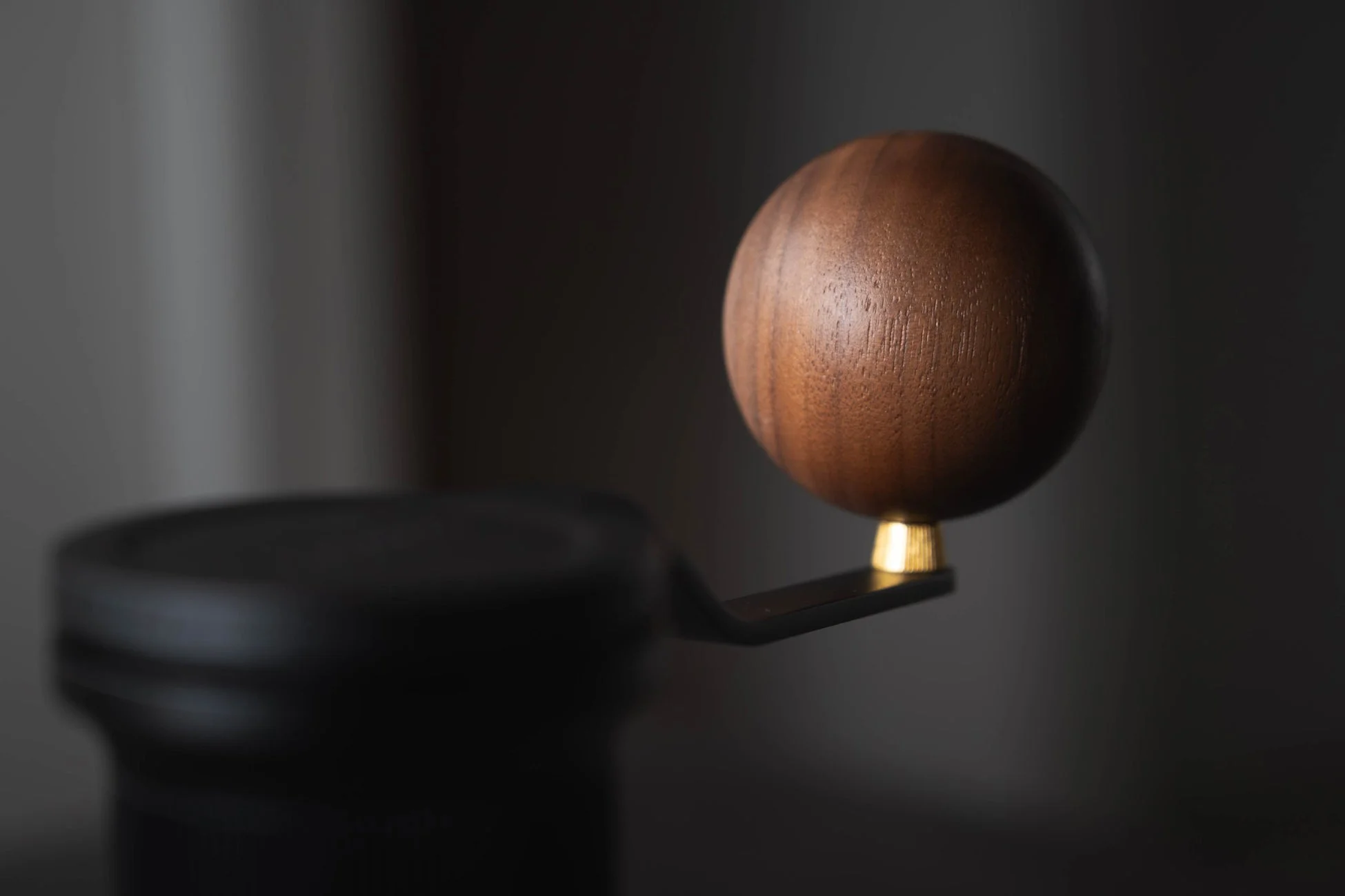 暗い背景に、木製の丸い取っ手が付いた黒いオブジェクトがクローズアップで写っています