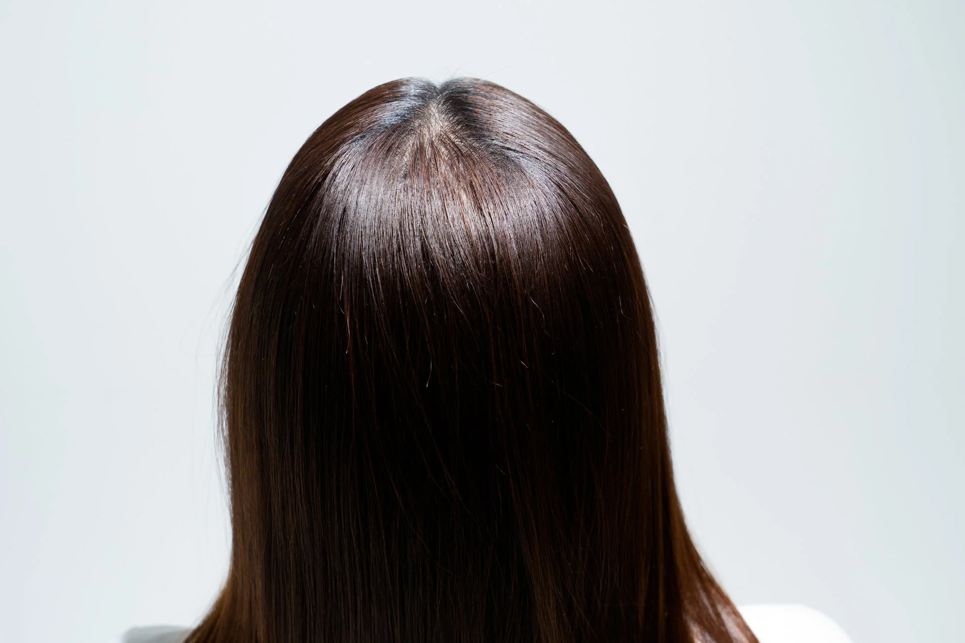 つやのあるダークブラウンのストレートヘアの女性の後ろ姿